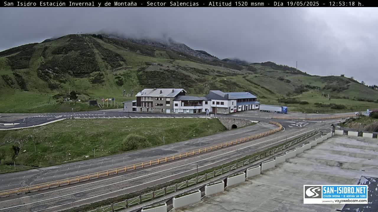 A mountaintop parking lot and roadway with a few buildings under an overcast sky.