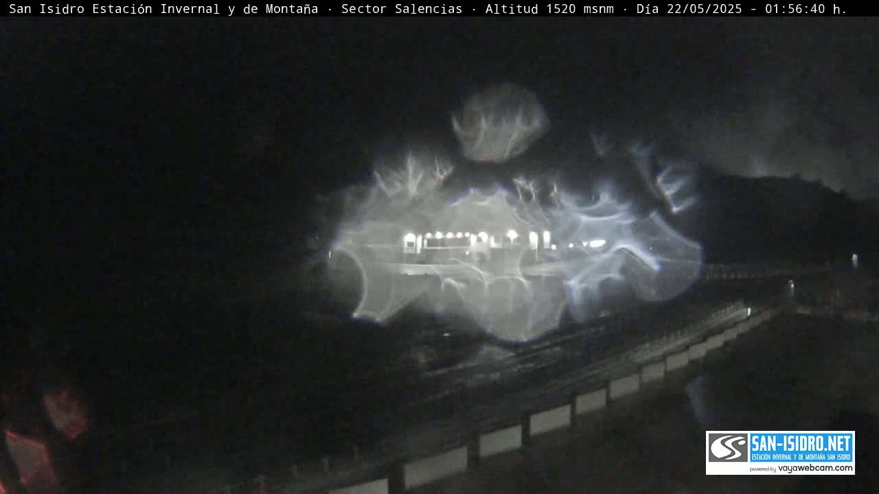 A nighttime, blurry image shows lights and what appears to be a building partially obscured by hazy weather conditions.