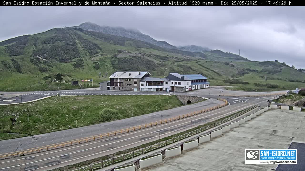 A mountainside resort with several buildings is visible, under an overcast sky.