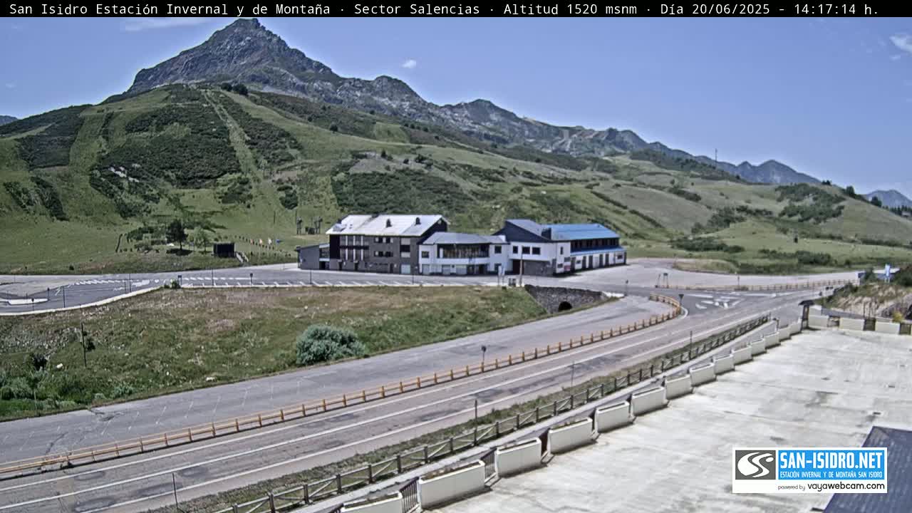 A mountainside parking lot and roadway with a building complex are visible under a clear sky.