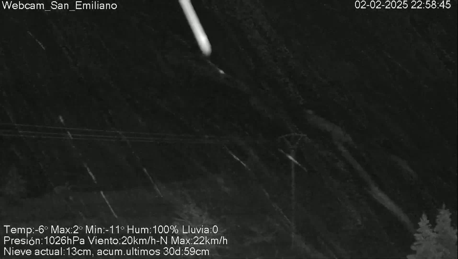 A nighttime, snowy scene shows falling snow illuminated by a bright meteor streaking across a dark sky.
