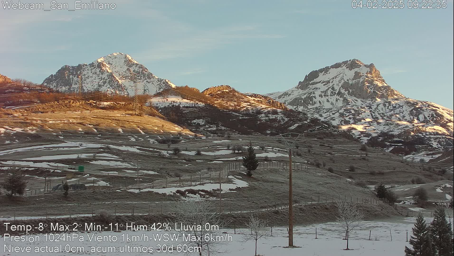 Two snow-capped mountains rise above a frost-covered valley under a clear, bright sky.