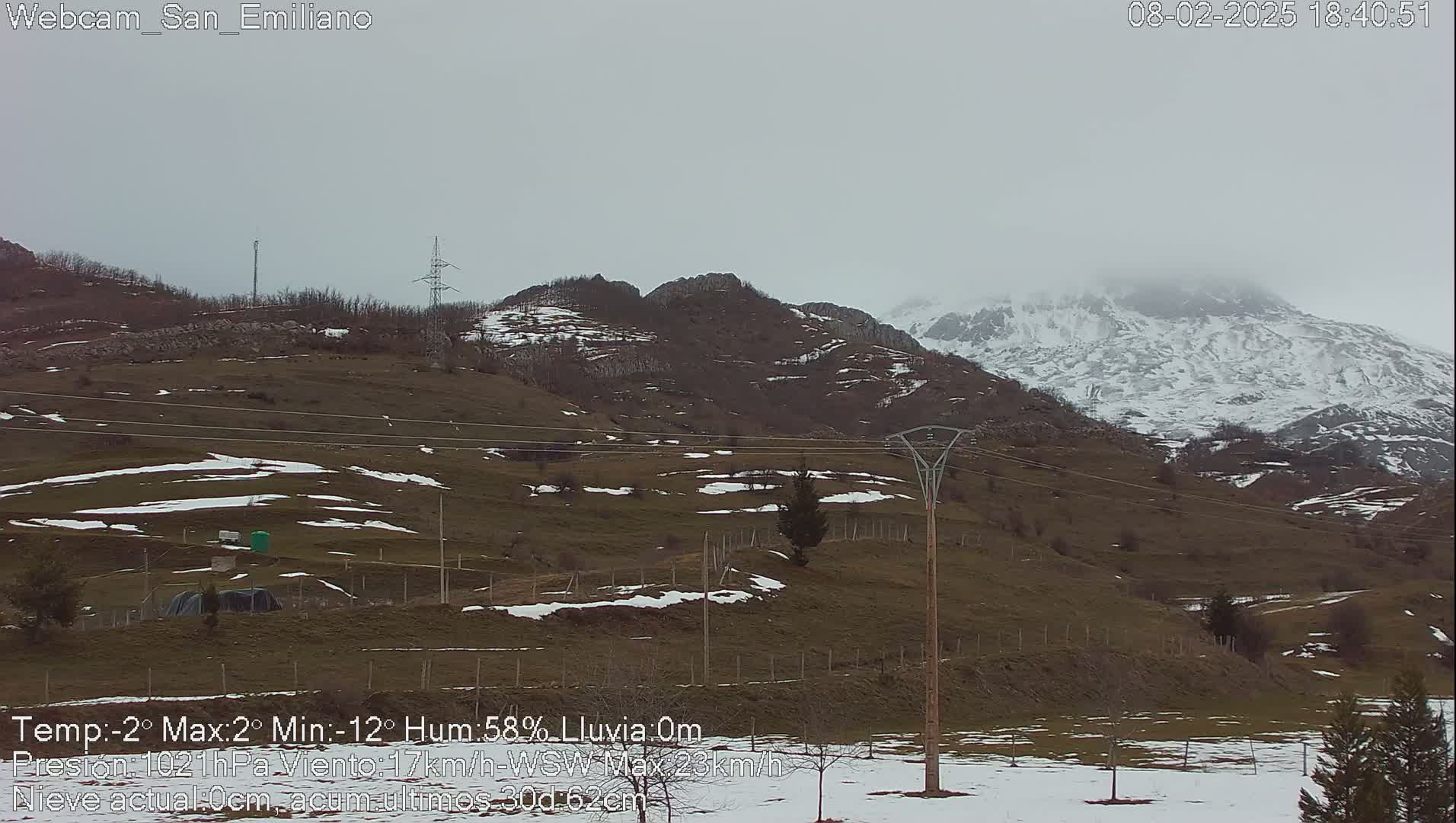 A snow-dusted, hilly landscape under an overcast sky with some patches of snow on the ground.