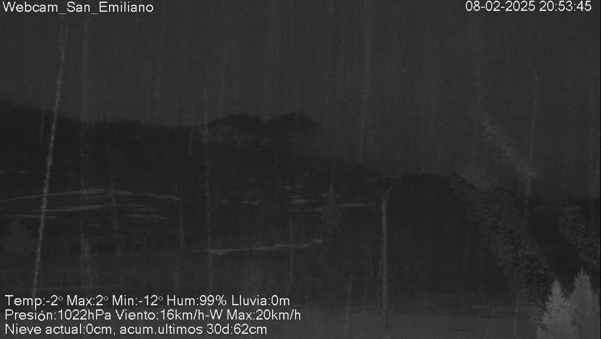 A nighttime, dark view of a mountainous landscape during rainy conditions with a low temperature.