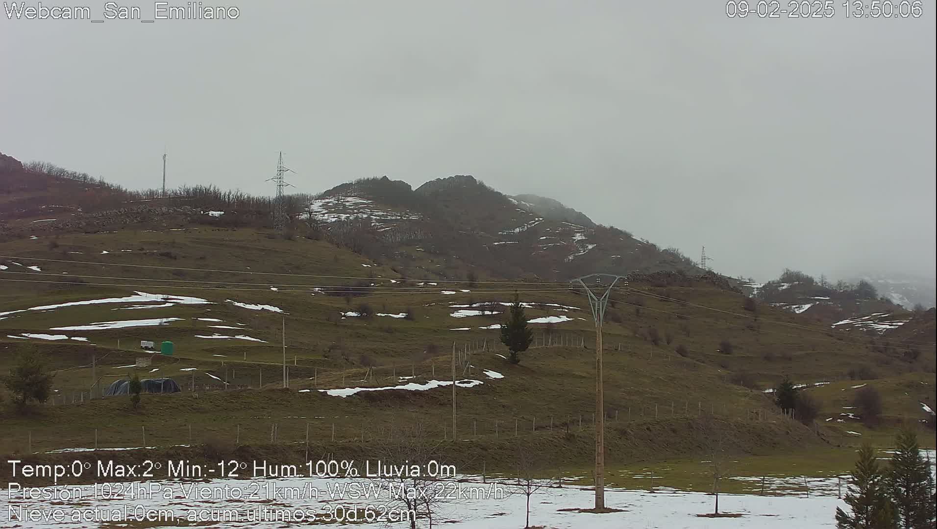 A hilly landscape with patches of snow under an overcast sky.