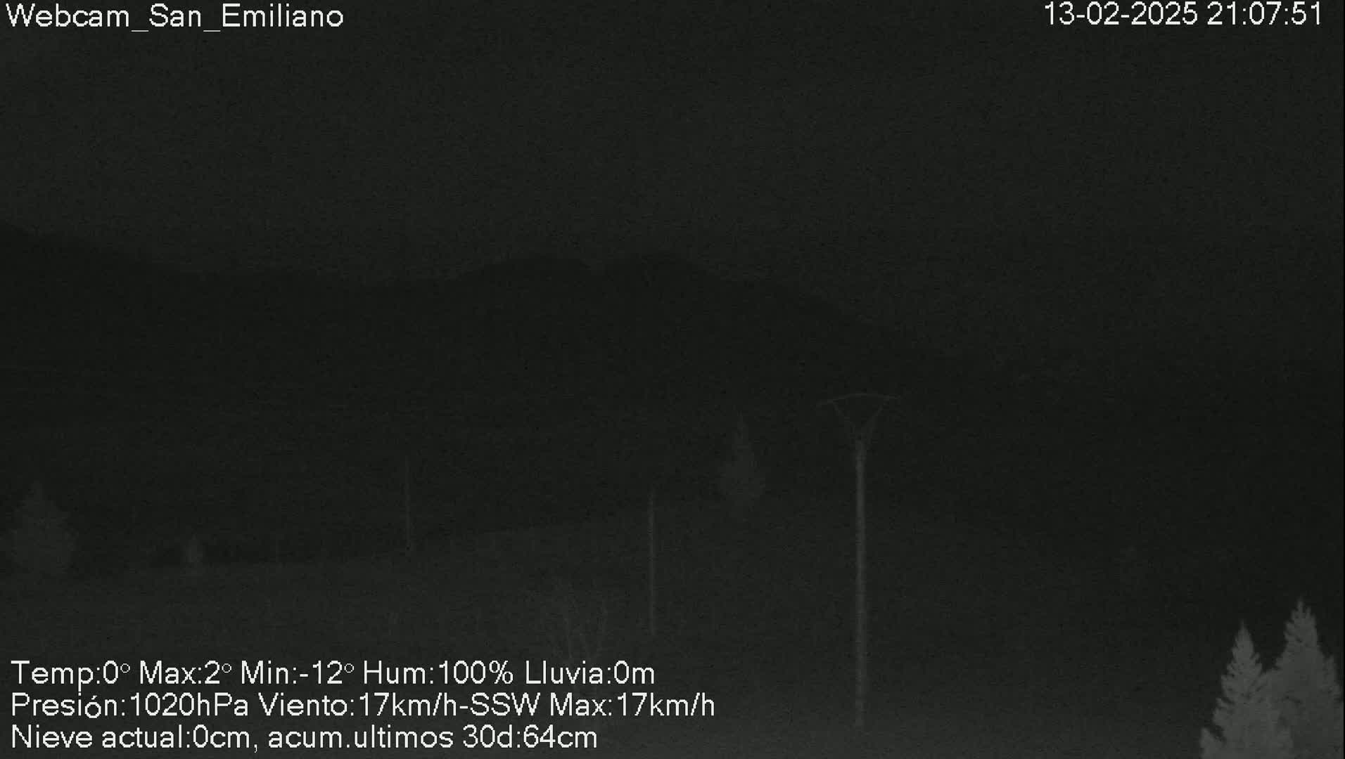 A nighttime, low-light outdoor scene shows dark silhouettes of trees and hills under a dark, overcast sky with 100% humidity.