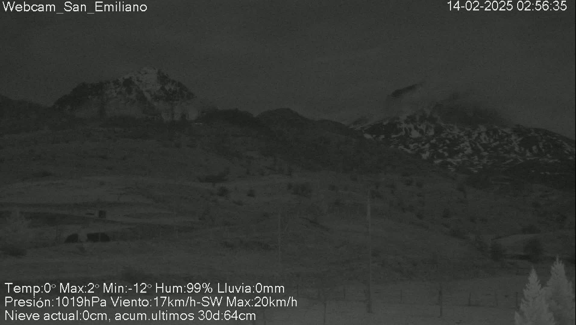 A nighttime view of snow-covered mountains under a dark sky.
