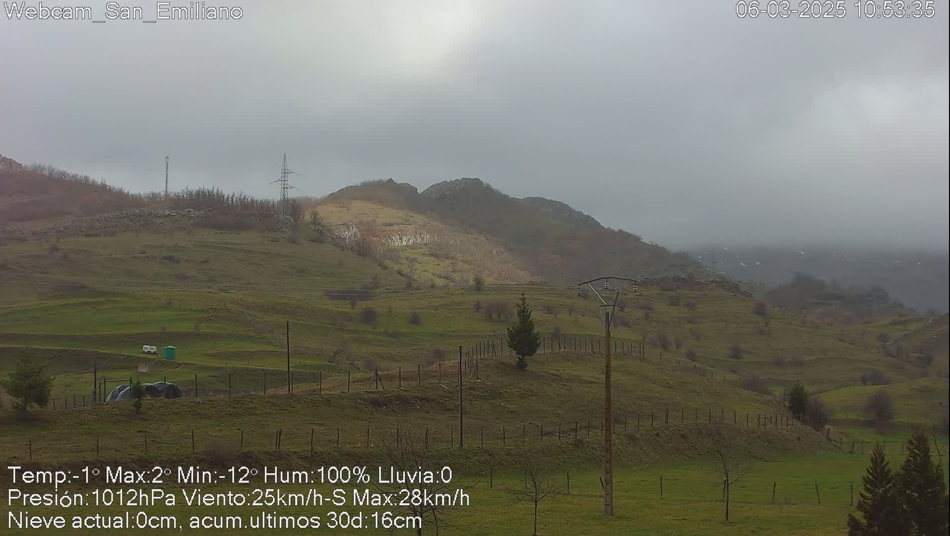 A misty, overcast view of rolling green hills and distant mountains under a gray sky.