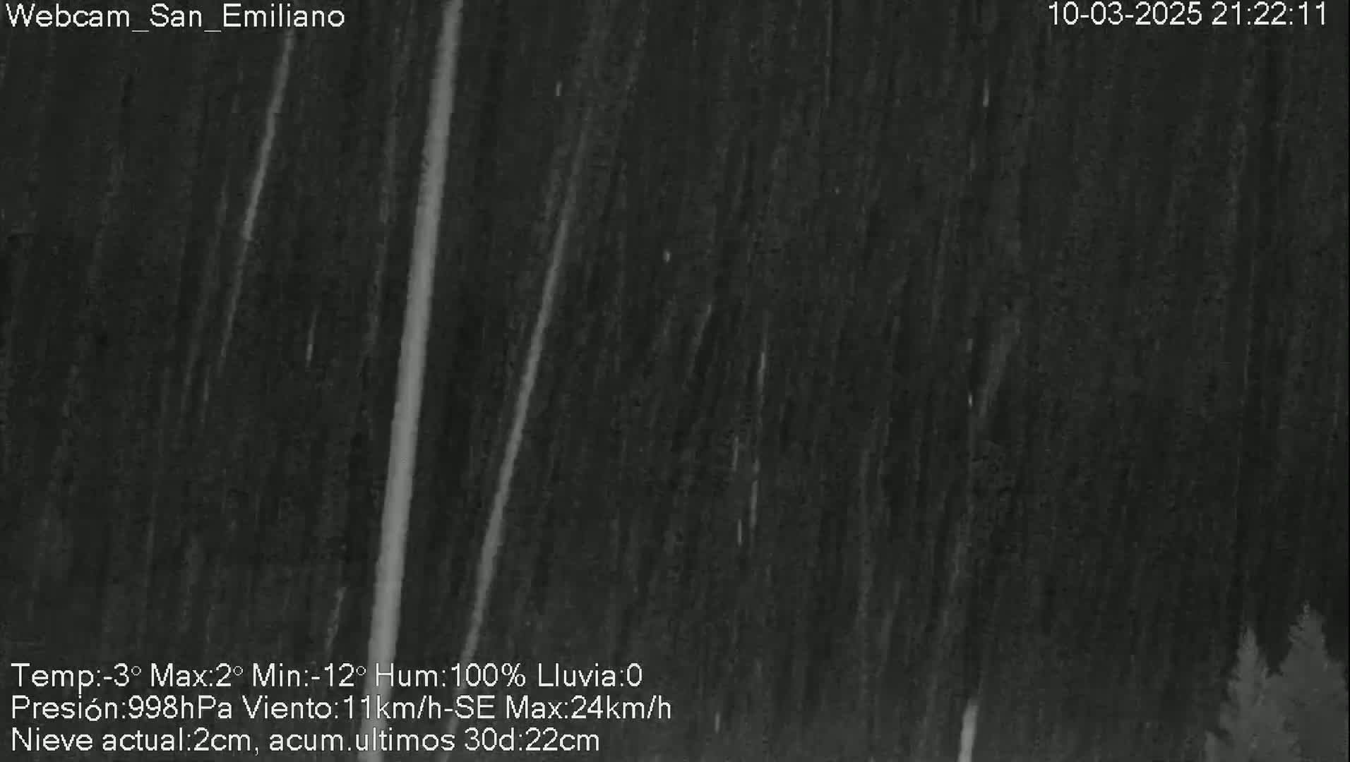 A nighttime, outdoor scene shows heavy rain falling, with some faint illumination from what appears to be a light source in the distance.
