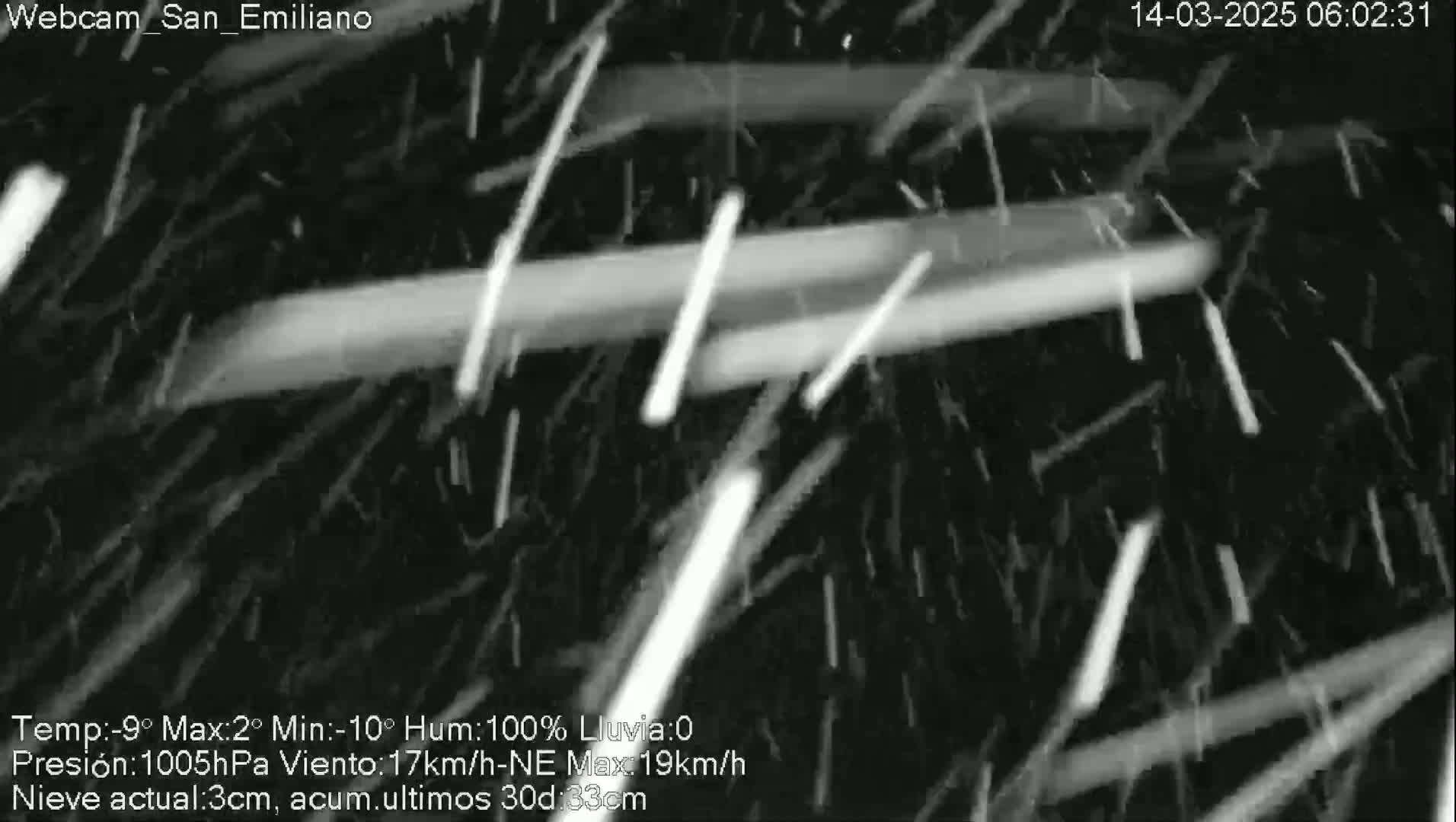 A nighttime, snow-filled scene shows streaks of light in the dark, created by falling snow illuminated by a light source.