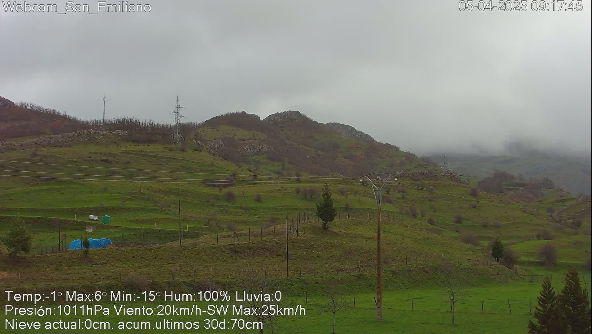 A misty, overcast view of rolling green hills and mountains under a gray sky.