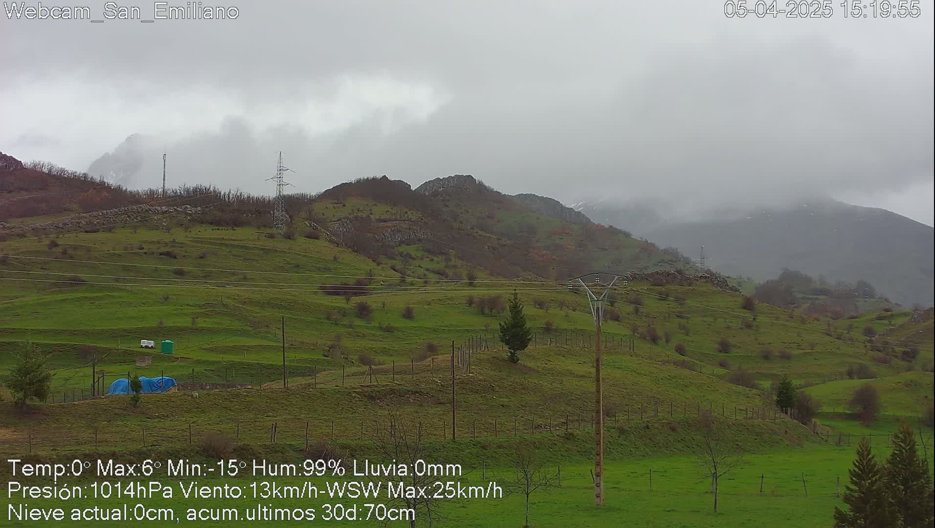 A foggy, overcast day reveals rolling green hills and distant mountains under a gray sky.