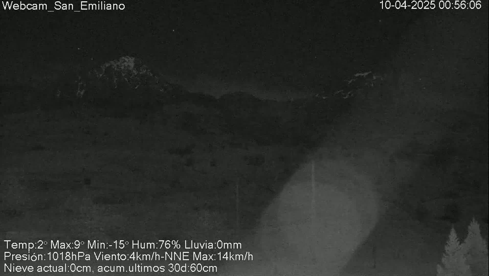 A nighttime, low-light view of a mountain range under a dark sky with some faint illumination on the mountaintops.