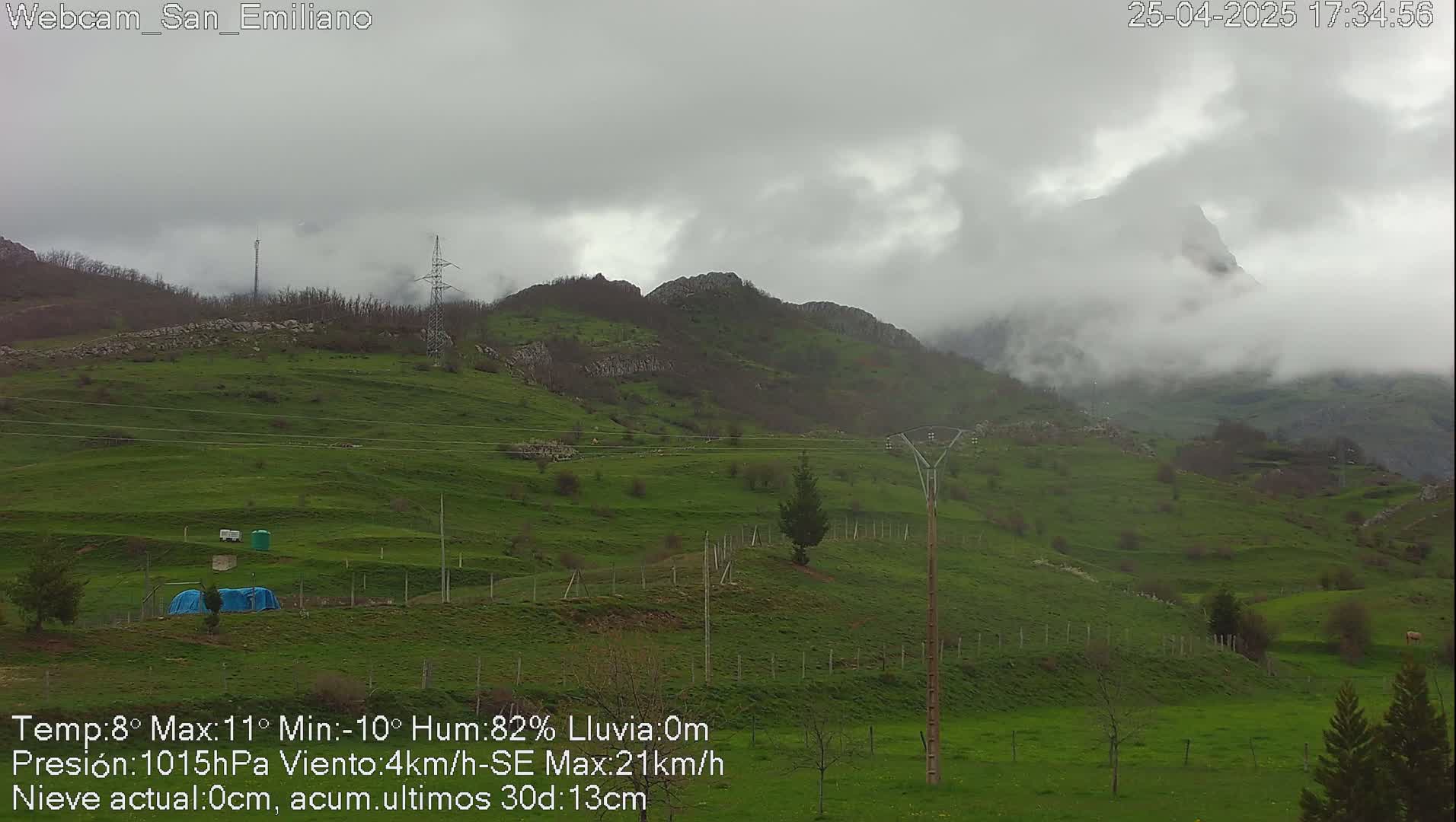 A cloudy, overcast day reveals rolling green hills and distant mountains partially obscured by fog.
