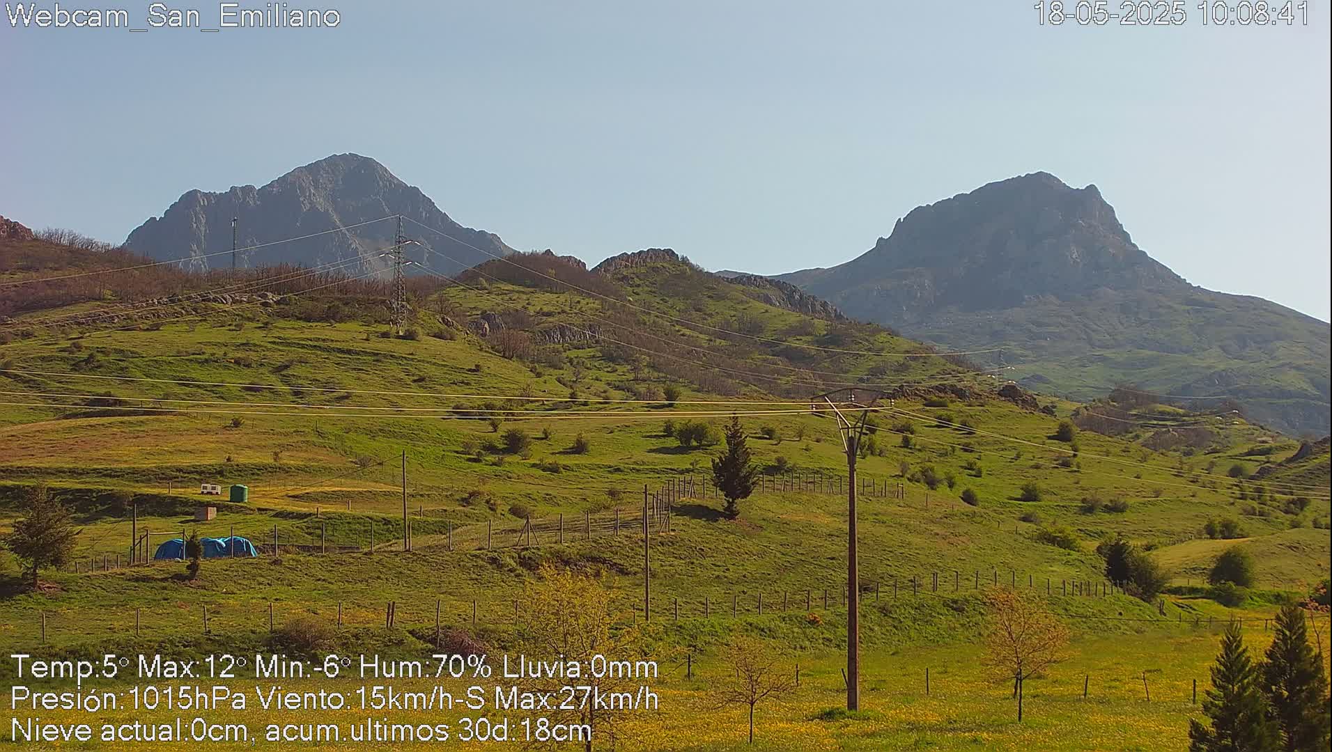 A sunny view of rolling green hills and distant mountains under a clear sky.