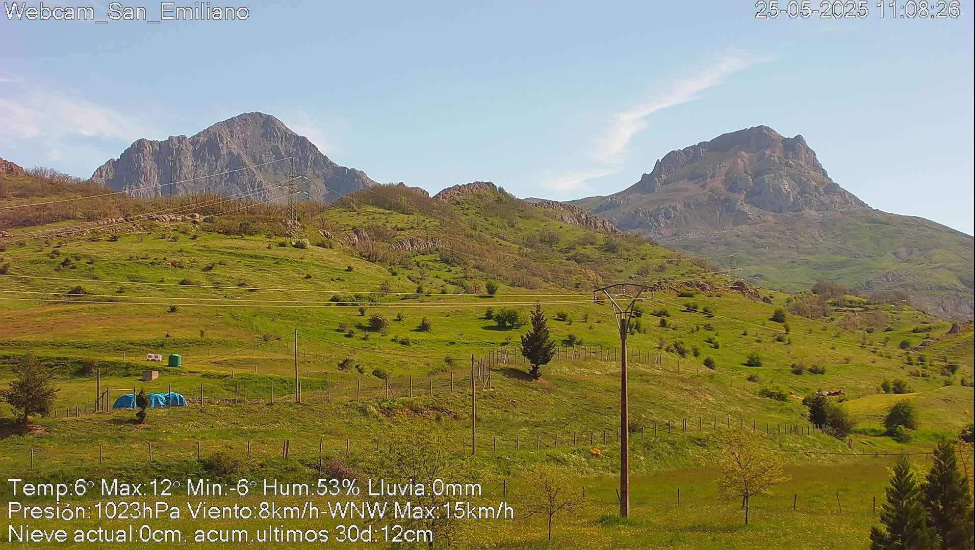A sunny view of rolling green hills and mountains under a clear sky.