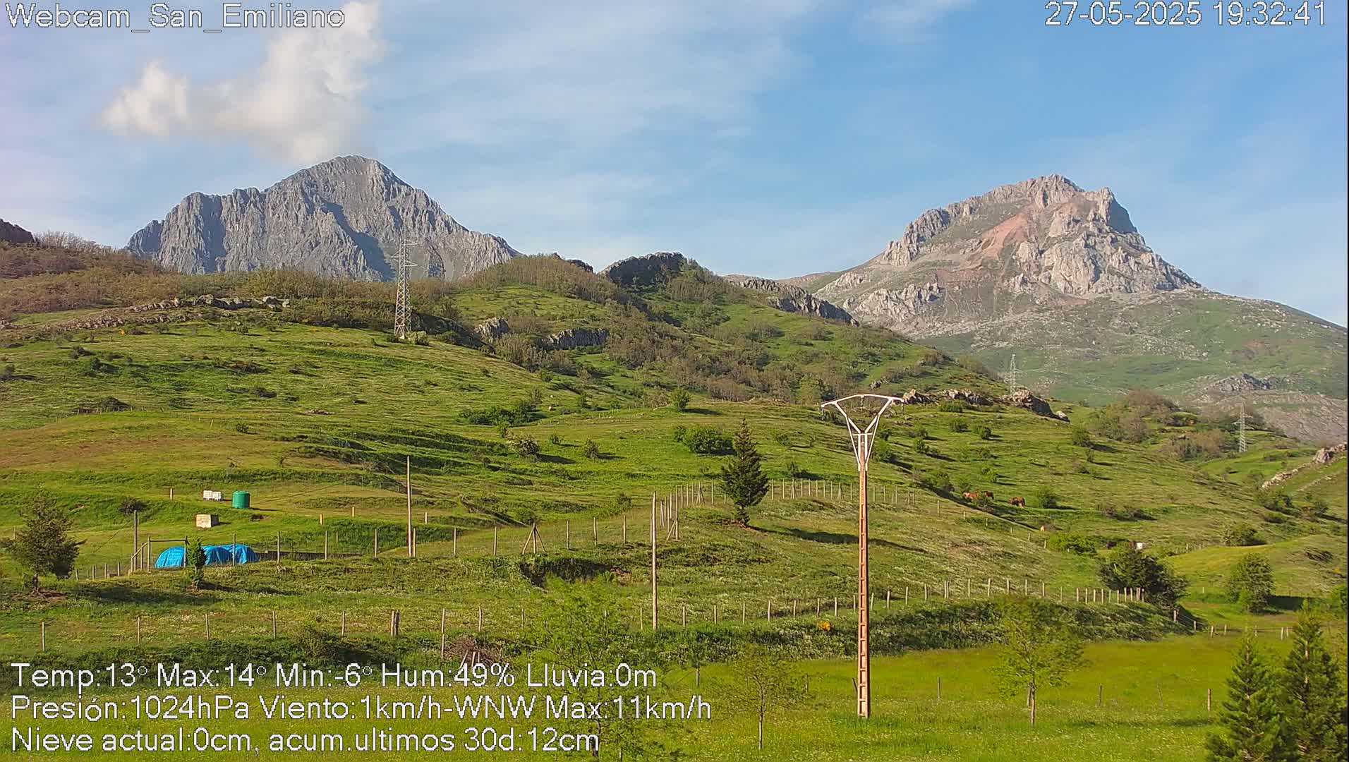 Rolling green hills and mountains under a mostly clear blue sky.
