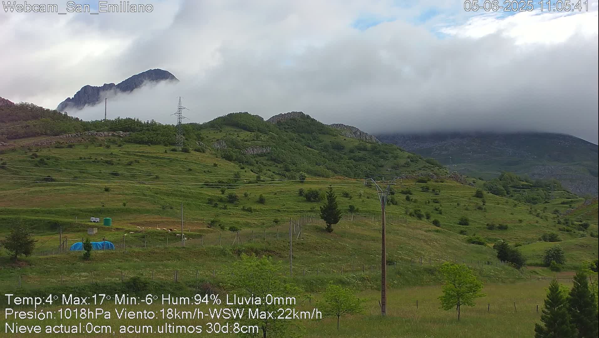 Rolling green hills and mountains shrouded in a cloudy, overcast sky.