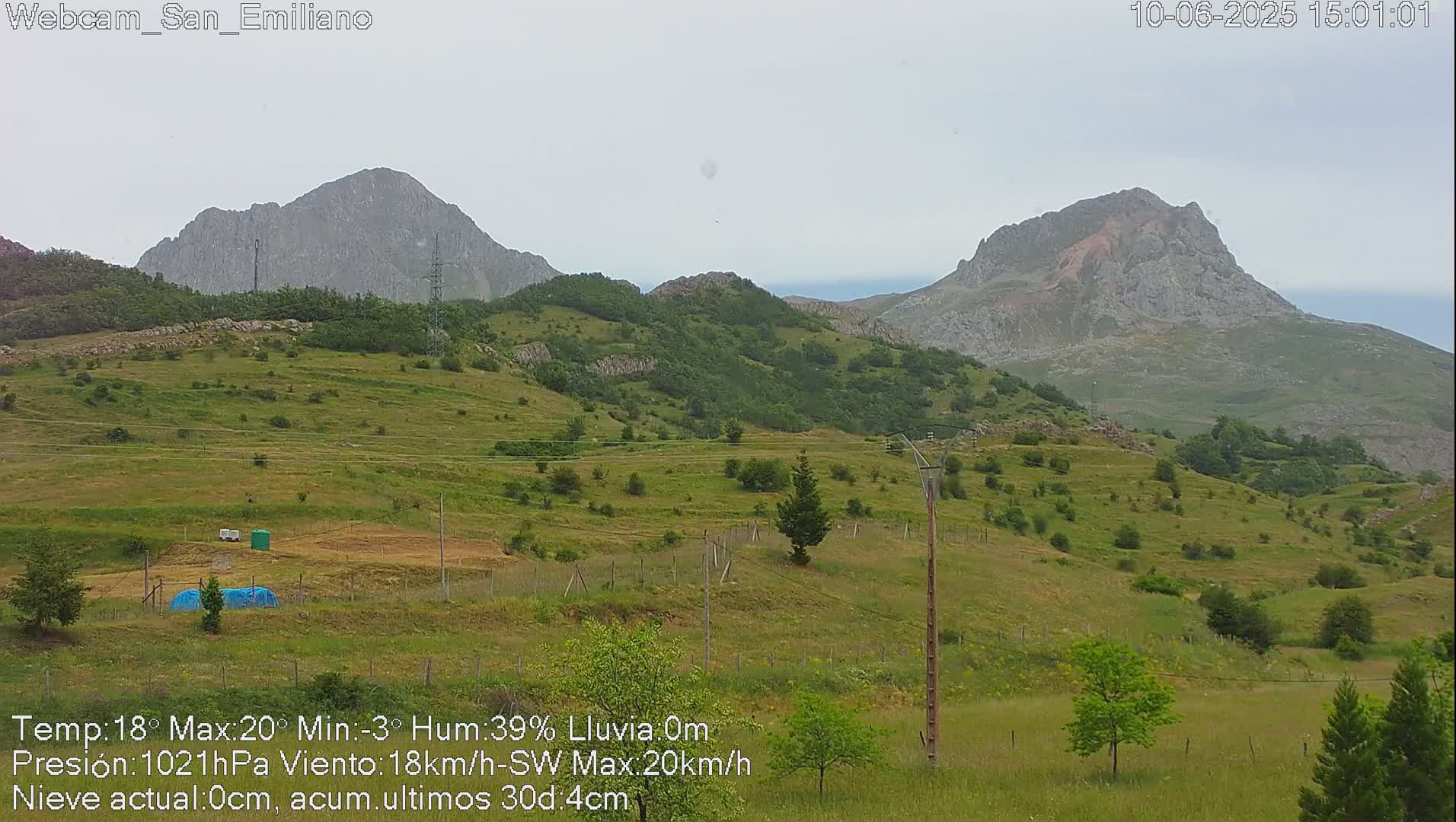 Rolling green hills and rocky mountains under an overcast sky.