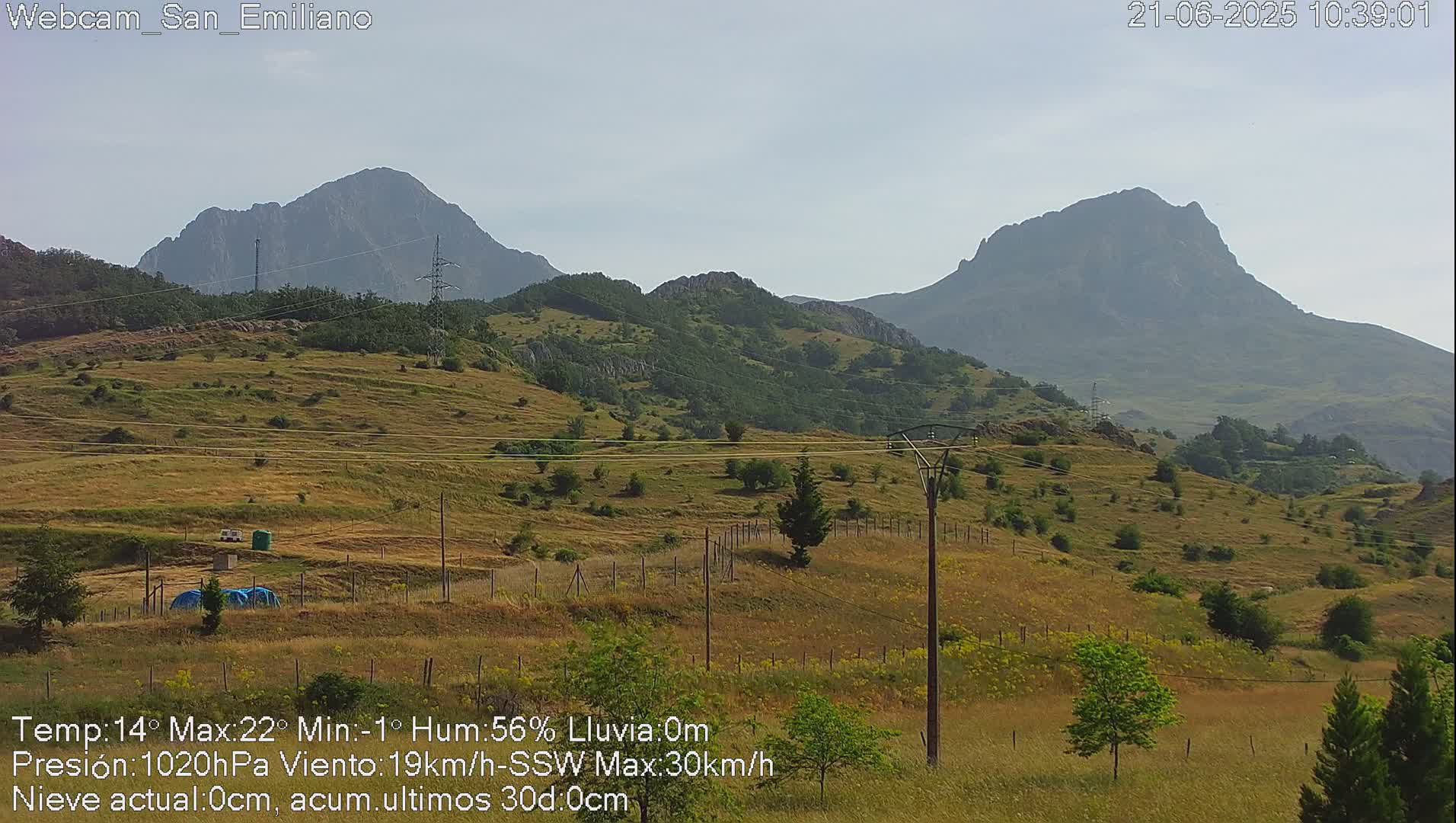 A view of rolling hills and distant mountains under a hazy sky.