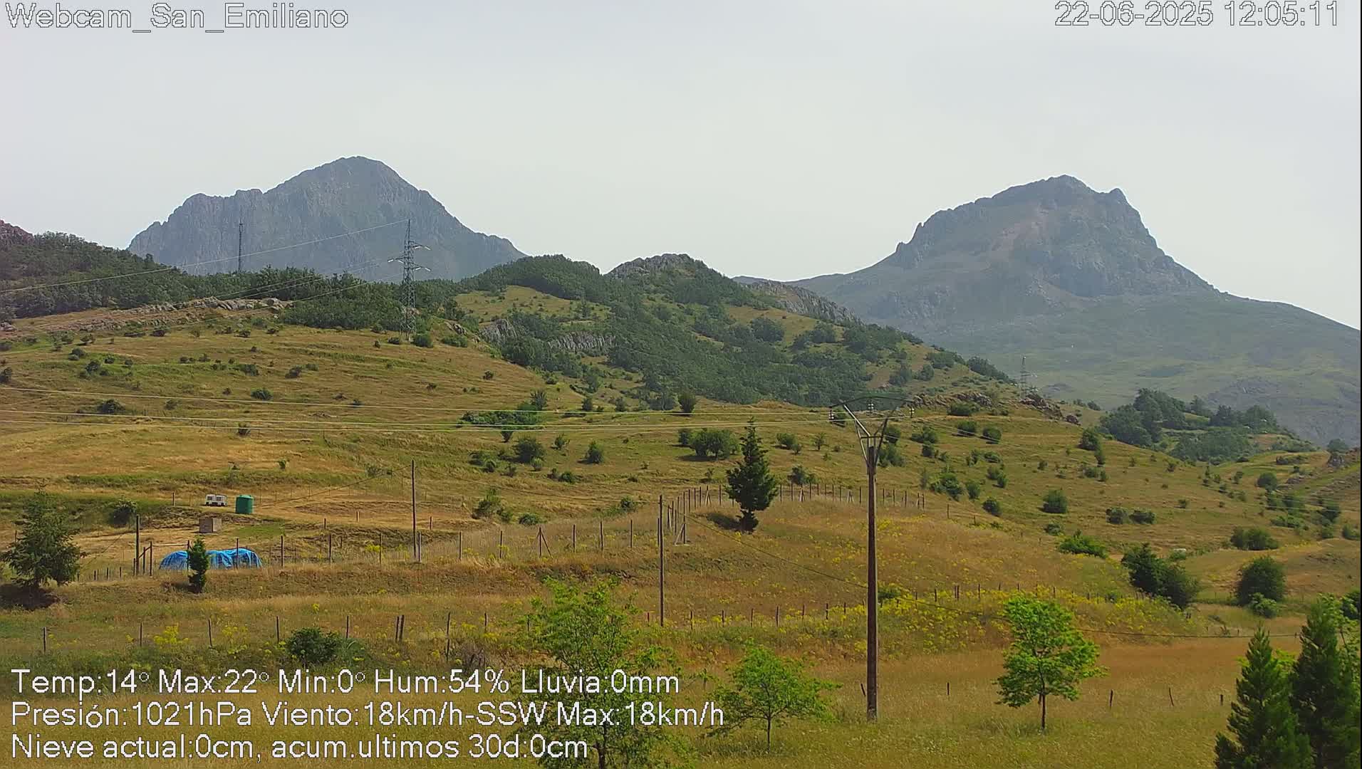 A view of rolling hills and mountains under a hazy sky.