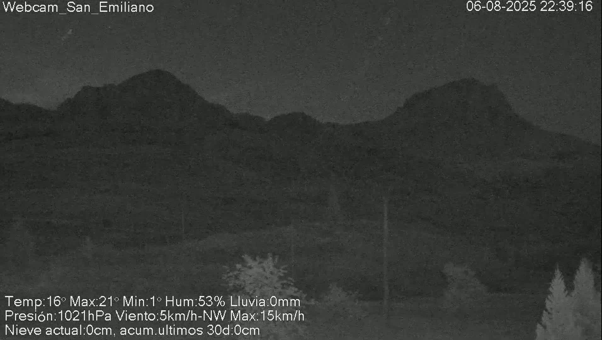 A nighttime view of dark, silhouetted mountains under a clear sky.