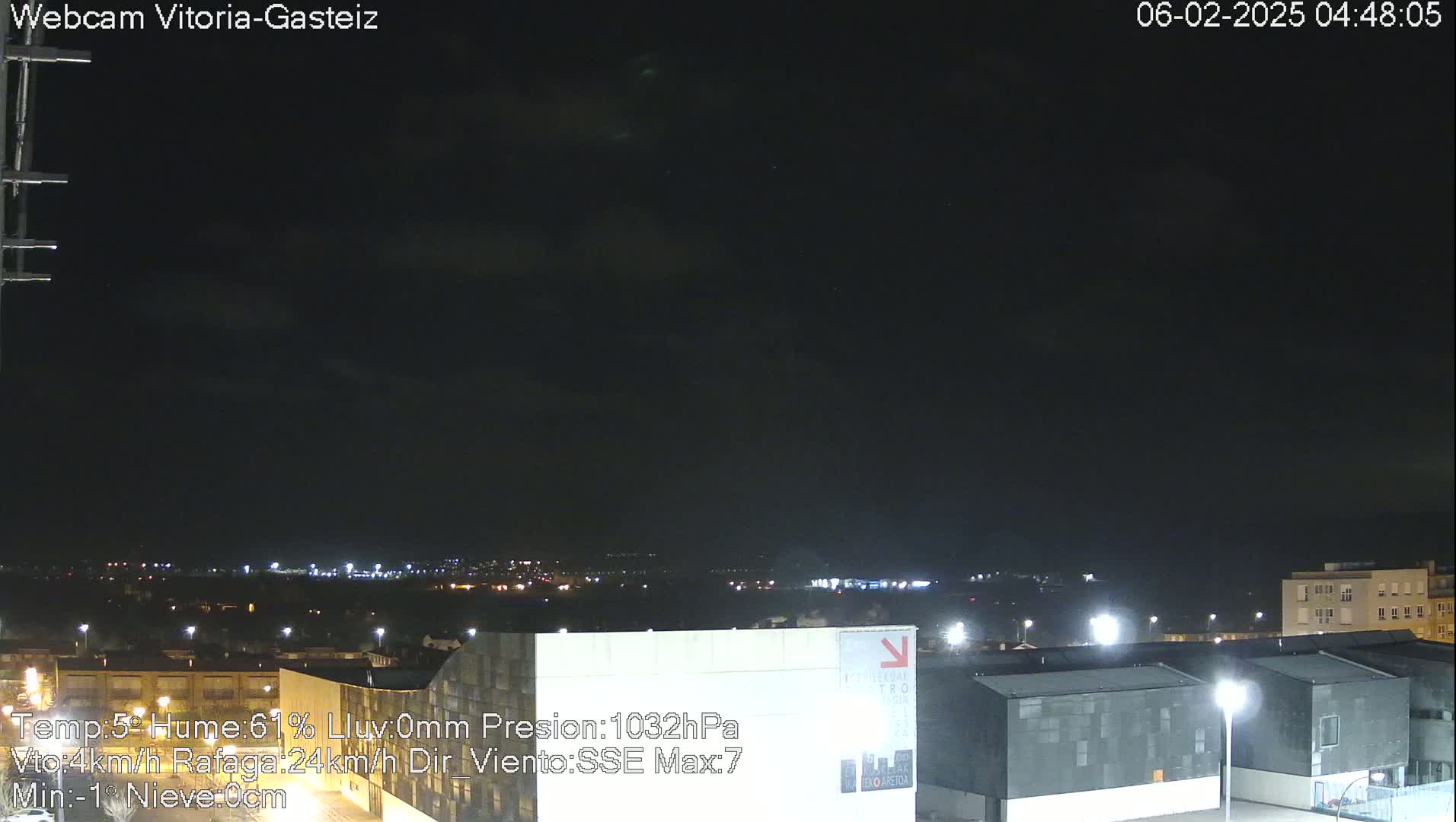 A nighttime view of a city illuminated by streetlights under a mostly clear, dark sky with a few clouds.