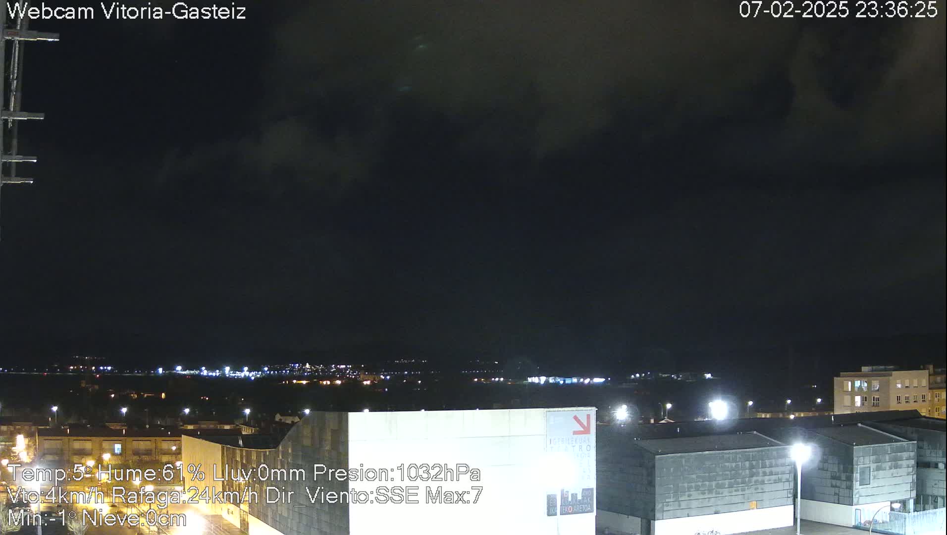 A nighttime view of a city skyline under a dark, cloudy sky.