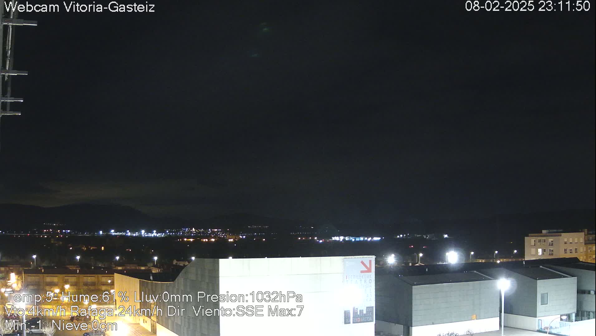 A nighttime view of a city illuminated by streetlights under a dark, mostly clear sky.