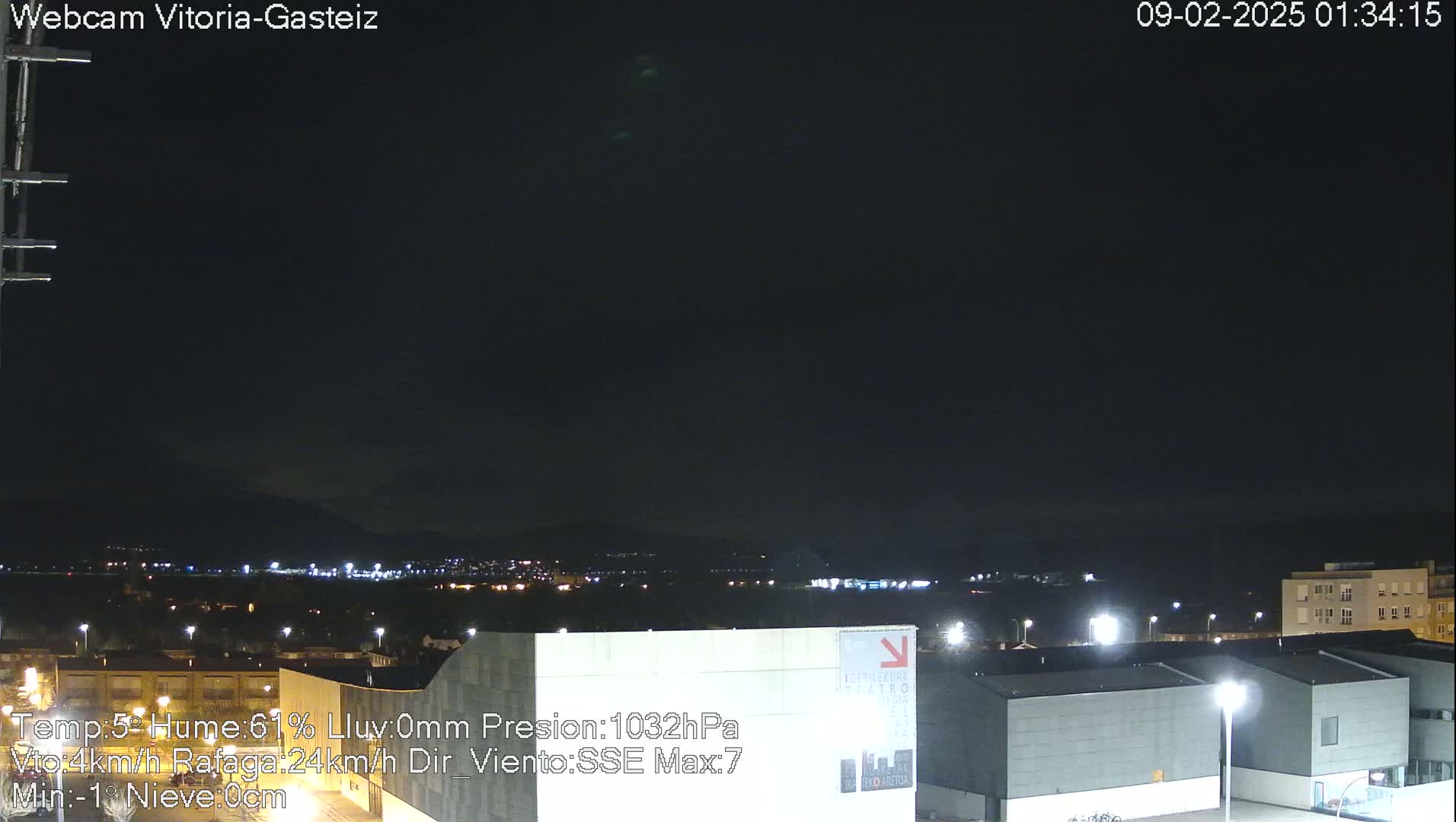 A nighttime view of a city with lights visible in the distance under a dark, clear sky.