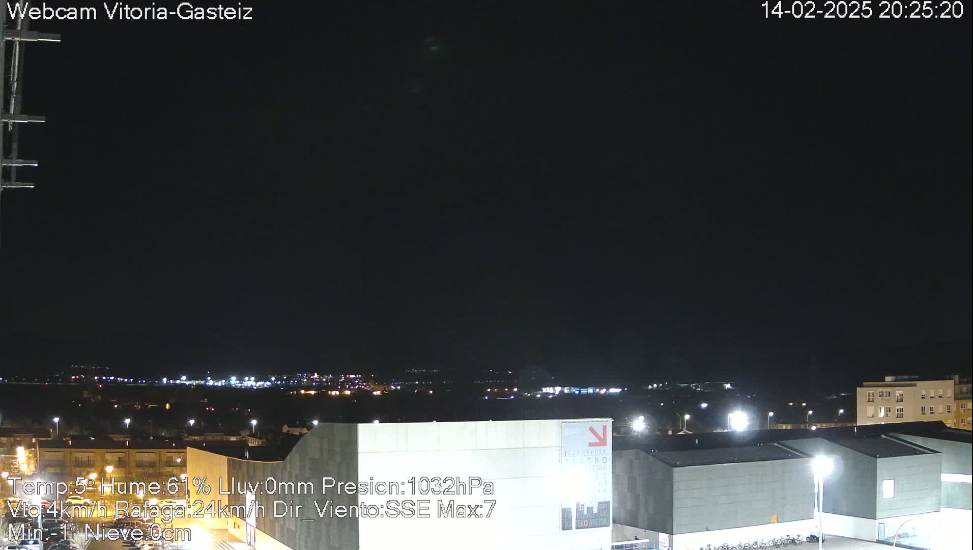 A nighttime view of a city skyline with illuminated buildings under a clear, dark sky.