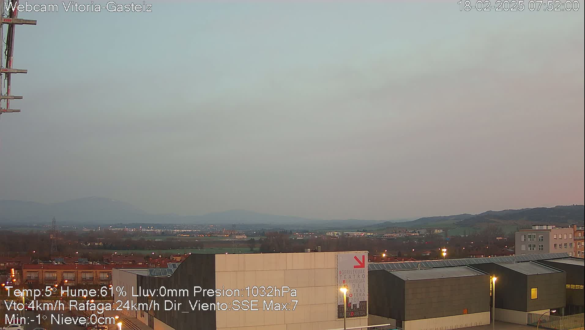A hazy, overcast morning view of a city with low-lying buildings and distant mountains.