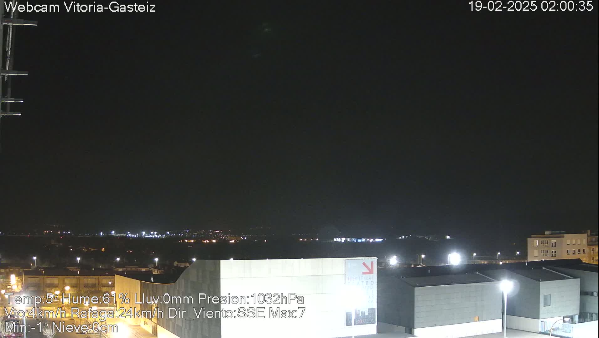 A nighttime long shot of a city landscape under a dark, clear sky, with some distant lights visible.
