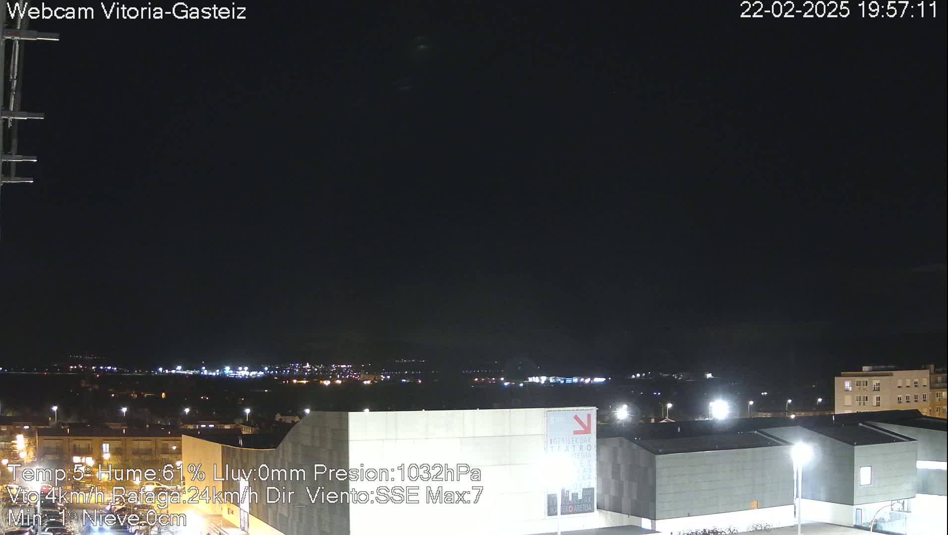 A nighttime view of a city skyline illuminated by lights, under a clear dark sky.
