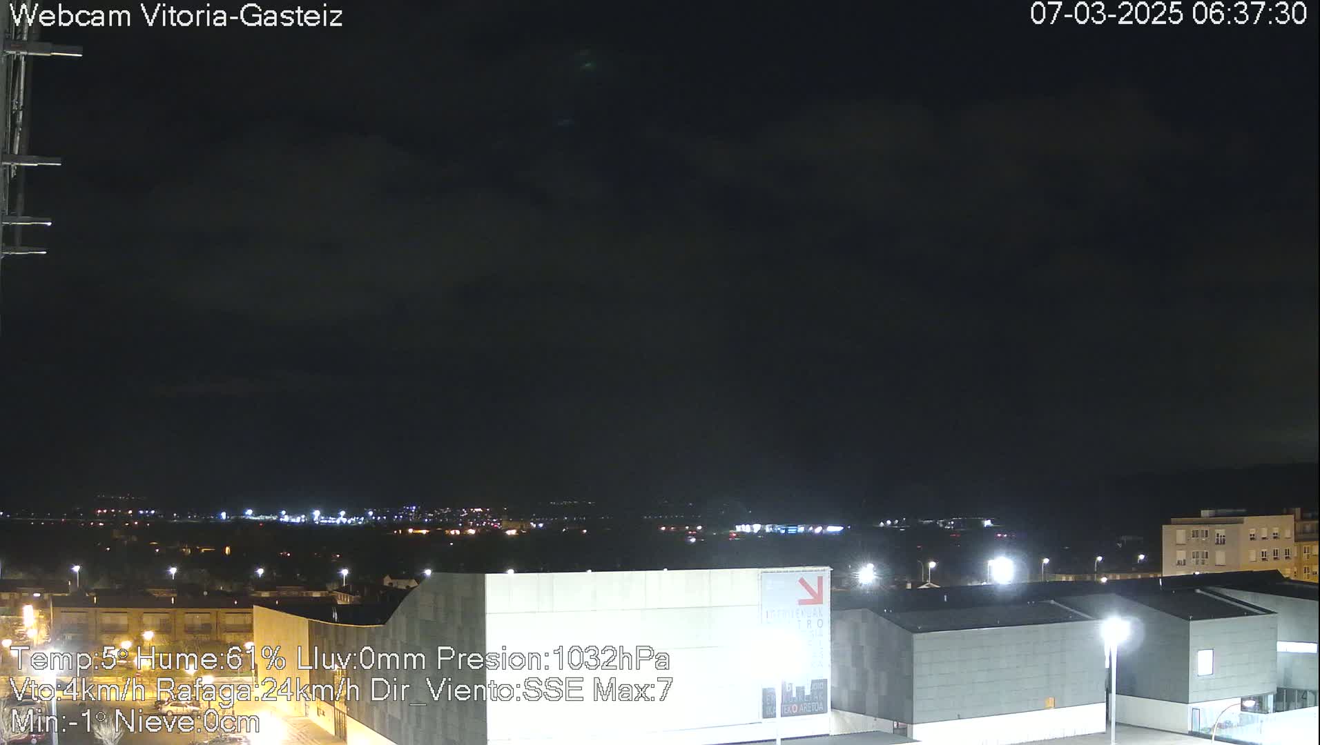 A nighttime view of a city under a mostly cloudy sky.