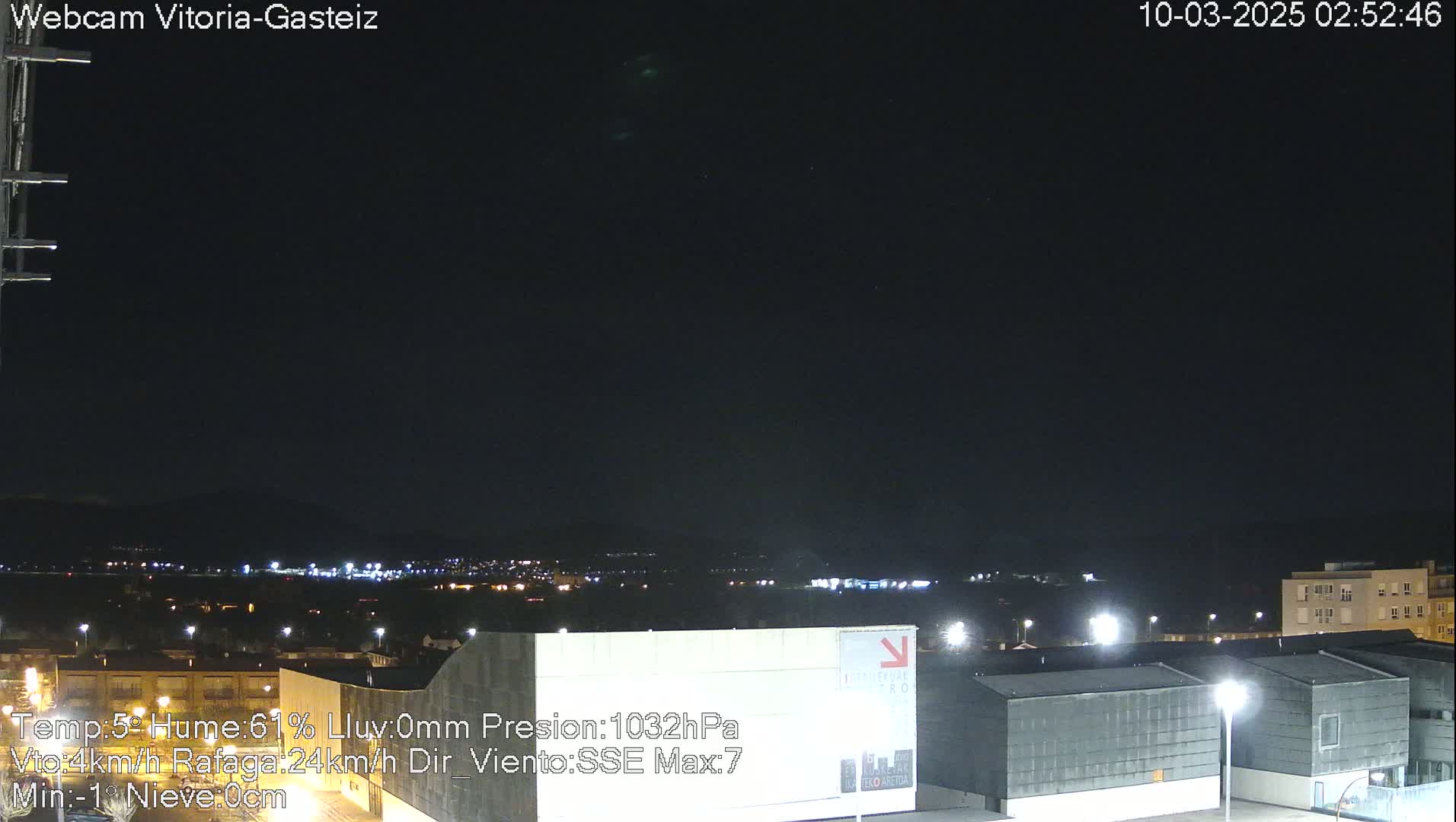A nighttime view of a city illuminated by streetlights under a dark, clear sky.