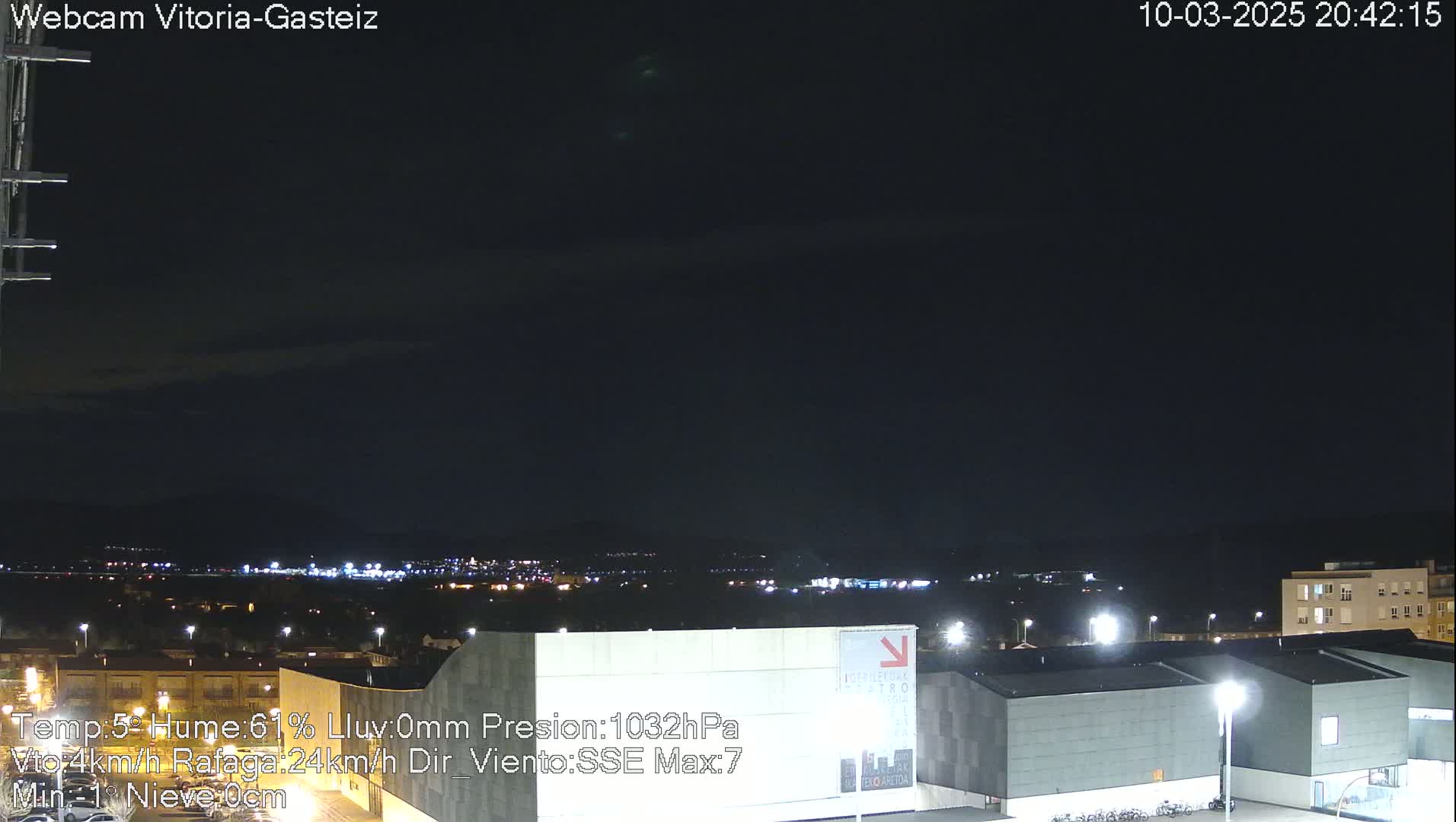A nighttime view of a city illuminated by lights under a dark, mostly clear sky.
