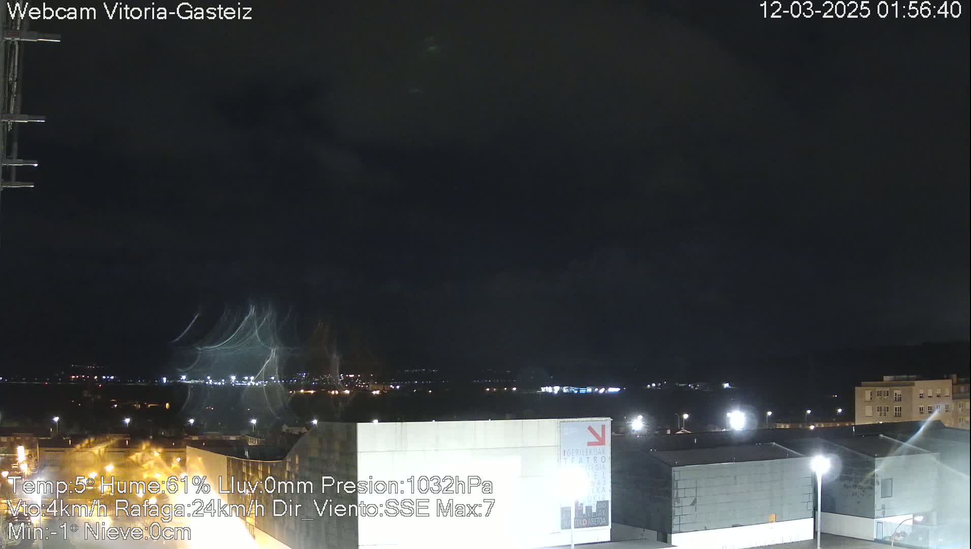 A nighttime view of a city illuminated by streetlights under a dark, mostly clear sky with some light cloud streaks.
