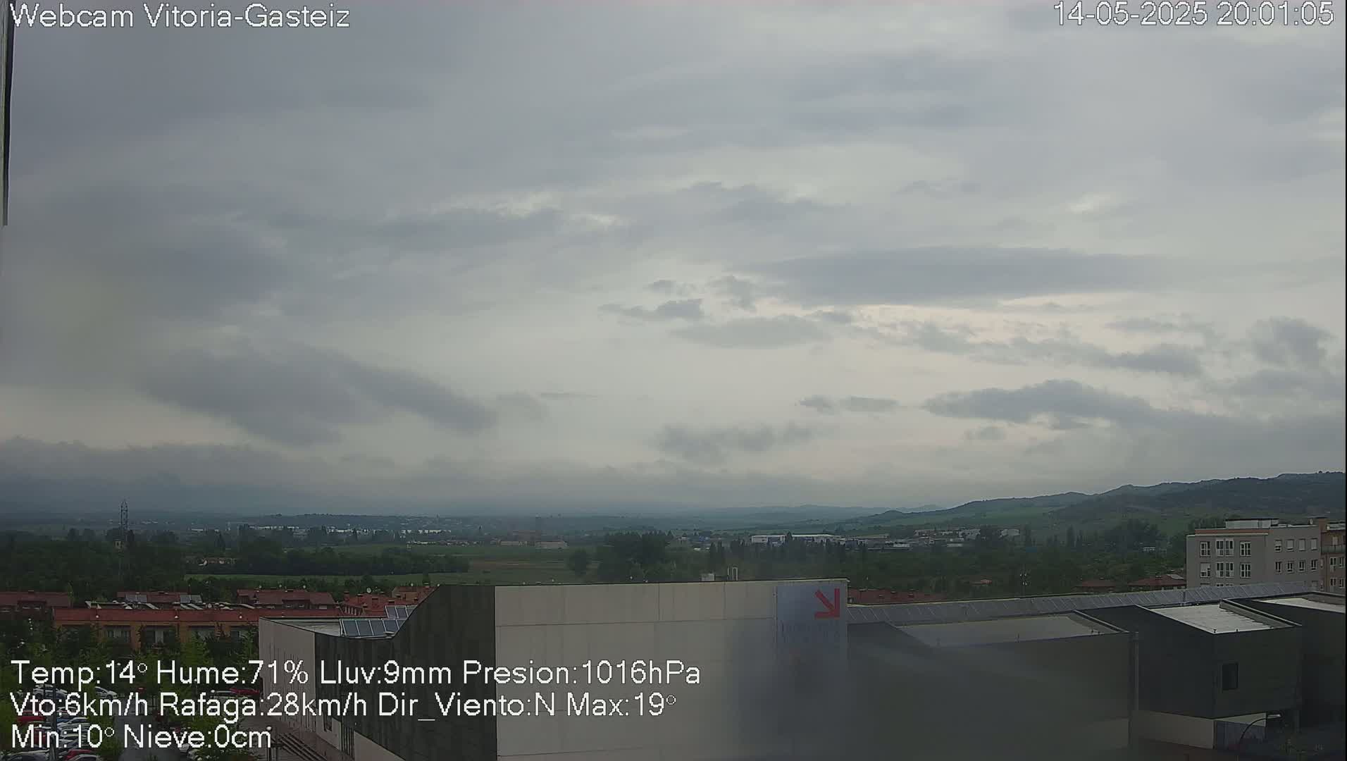 A view of a town and distant hills under an overcast sky.