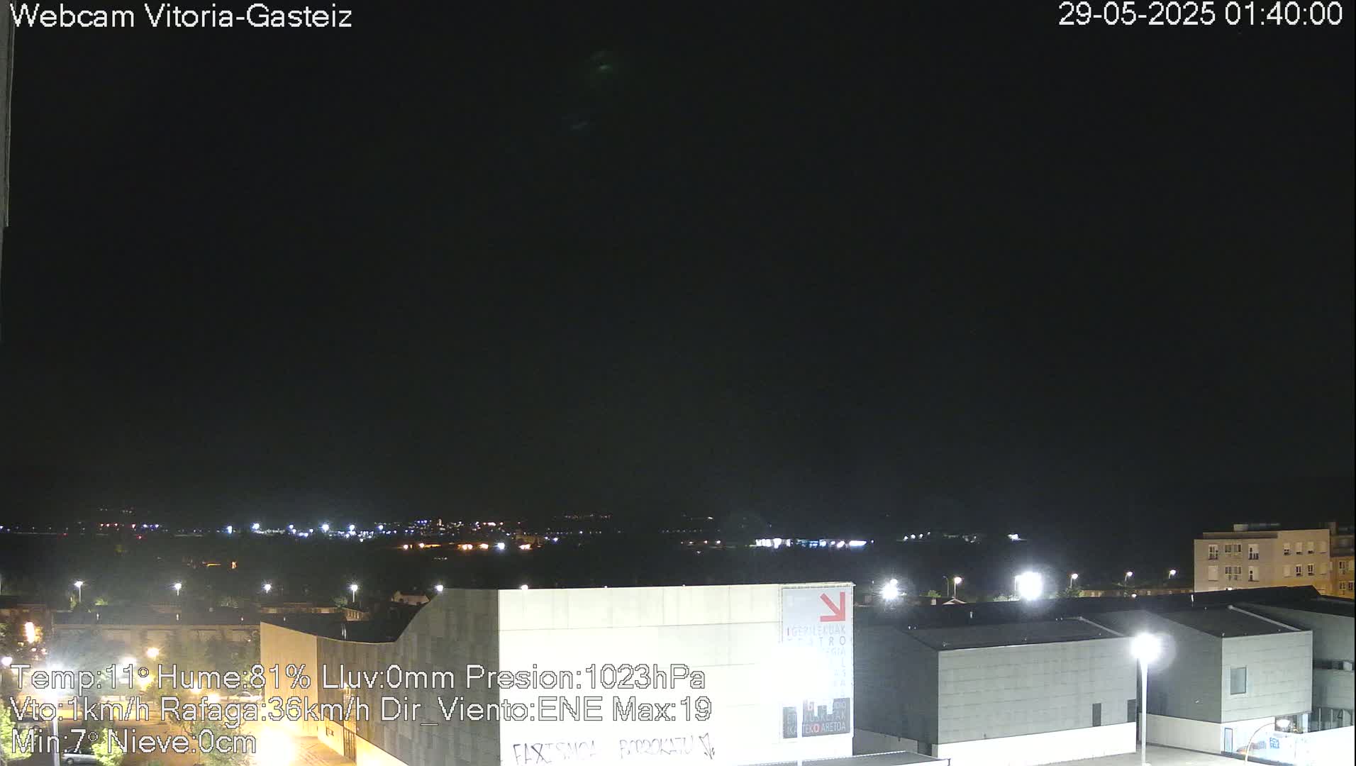 A nighttime view of a city with low-level lights visible in the distance under a clear, dark sky.