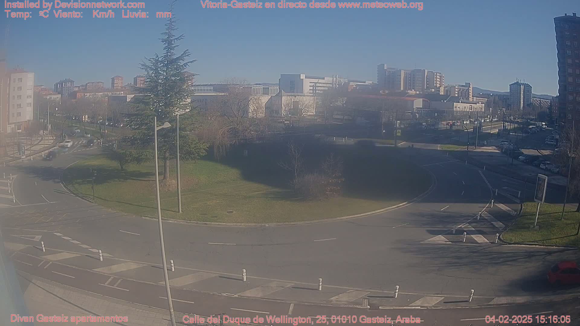 A sunny, hazy view of a traffic circle in a city with buildings in the background.