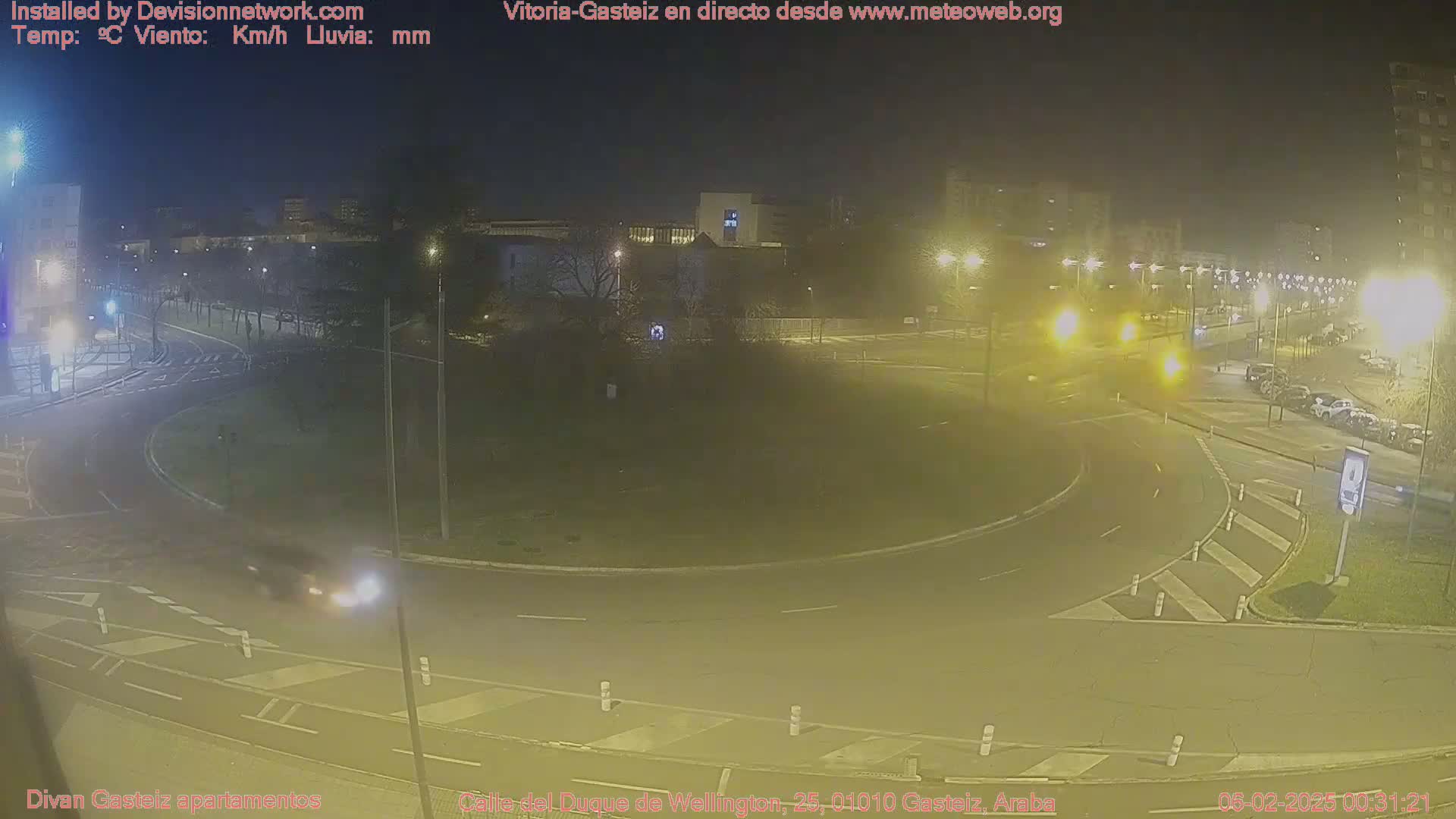 A nighttime view of a roundabout with a few cars and streetlights illuminating the scene.