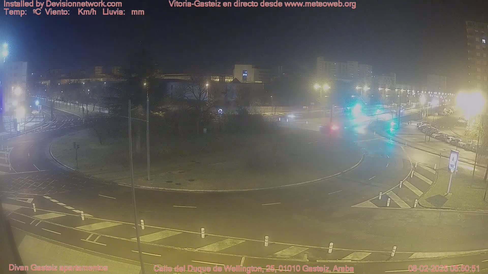 A nighttime view of a roundabout with cars and streetlights, under clear skies.