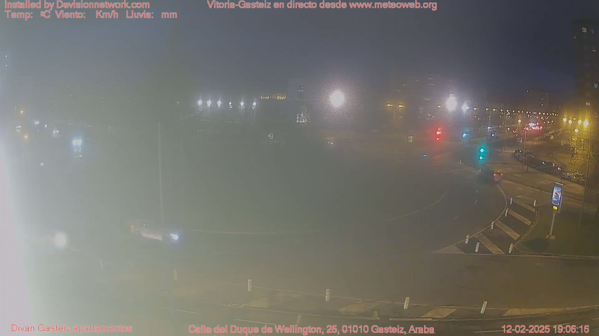 A hazy night scene shows a roundabout with sparse traffic and streetlights illuminating the surroundings.