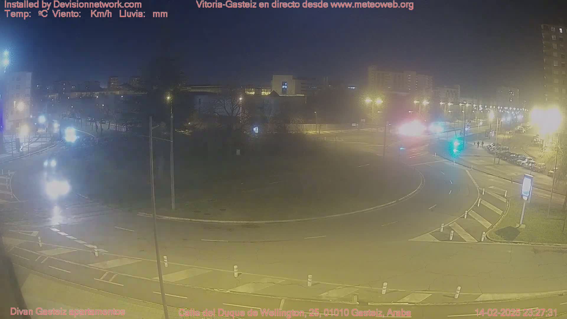 A nighttime view of a roundabout with cars and streetlights, under clear skies.
