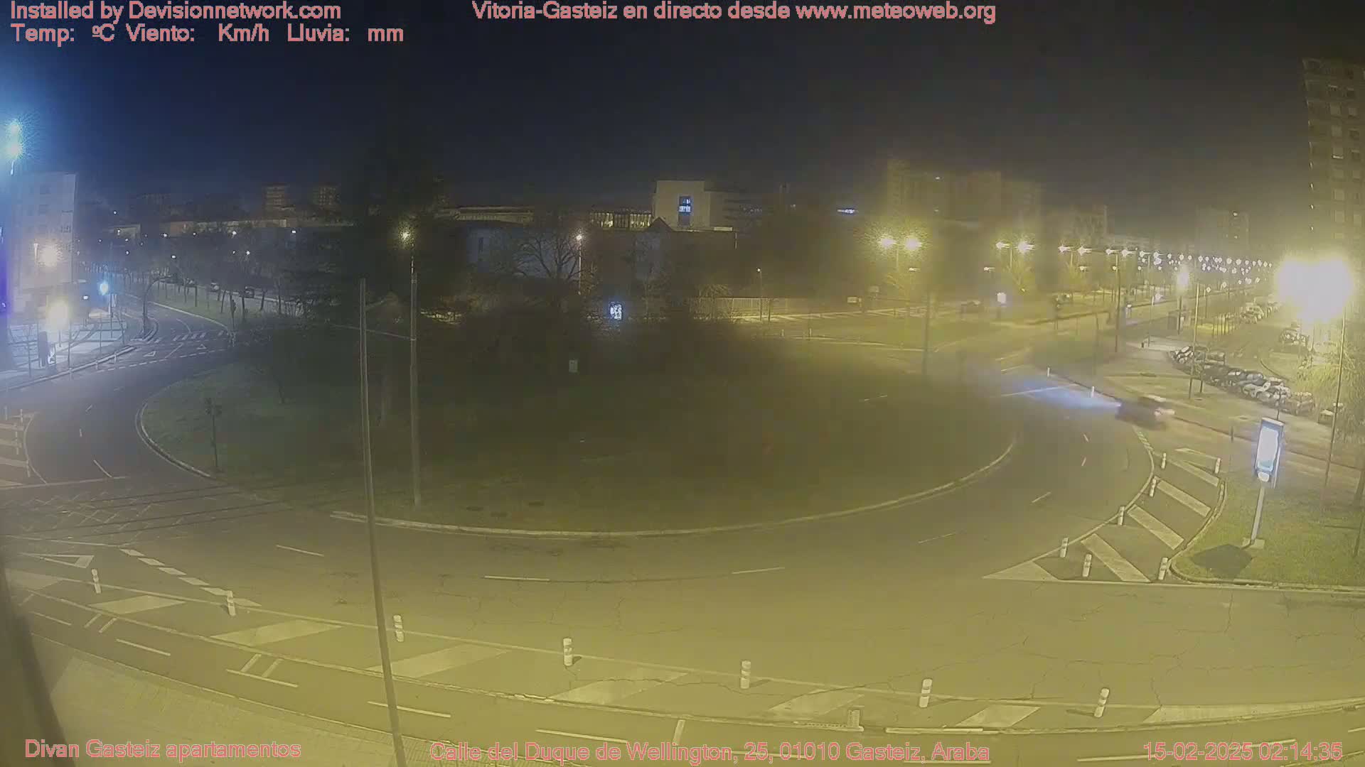 A nighttime view of a roundabout and surrounding streets, illuminated by streetlights under hazy conditions.