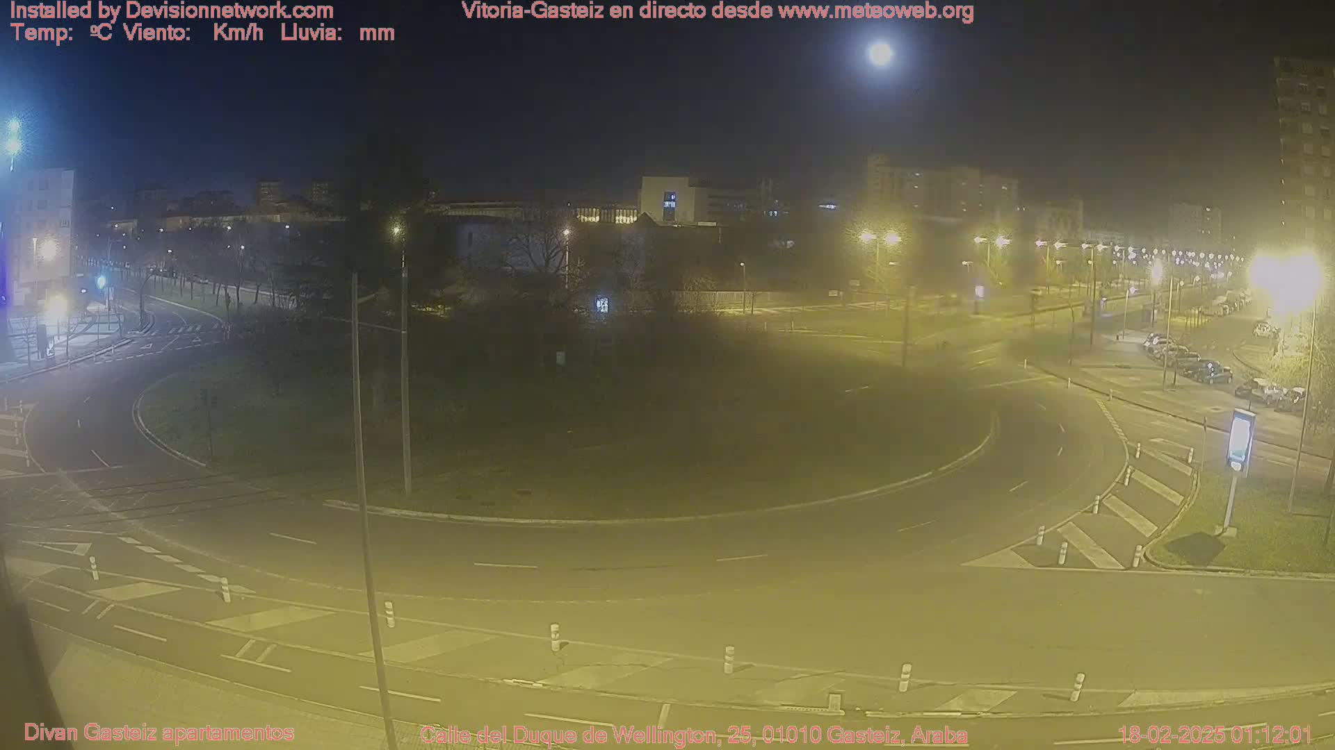 A nighttime view of a roundabout and surrounding streets, illuminated by streetlights under a clear moonlit sky.