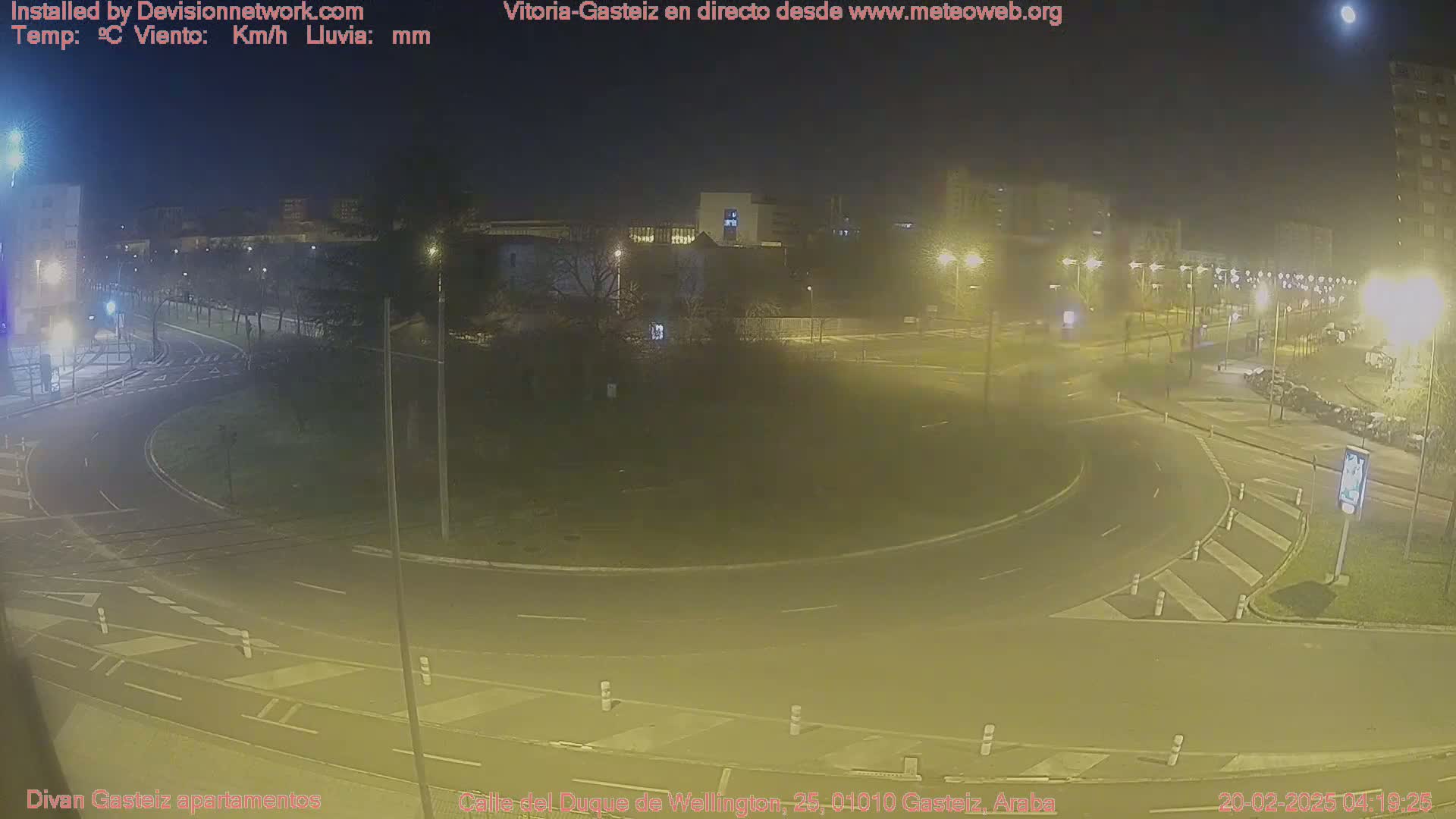 A nighttime view of a roundabout and surrounding streets, illuminated by streetlights under a clear sky with a visible moon.