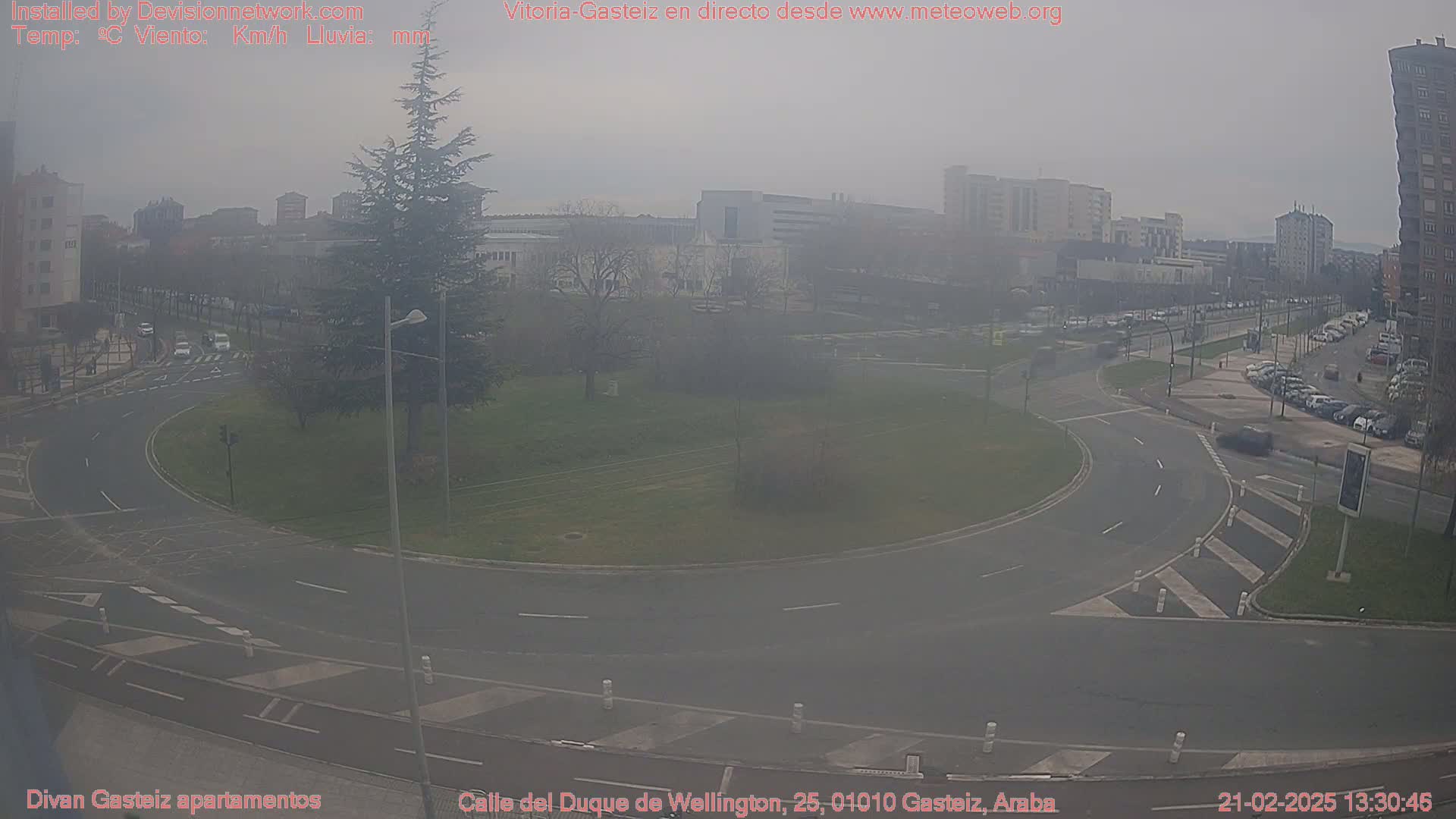 A hazy view of a roundabout in a city, with cars and buildings visible in the distance.