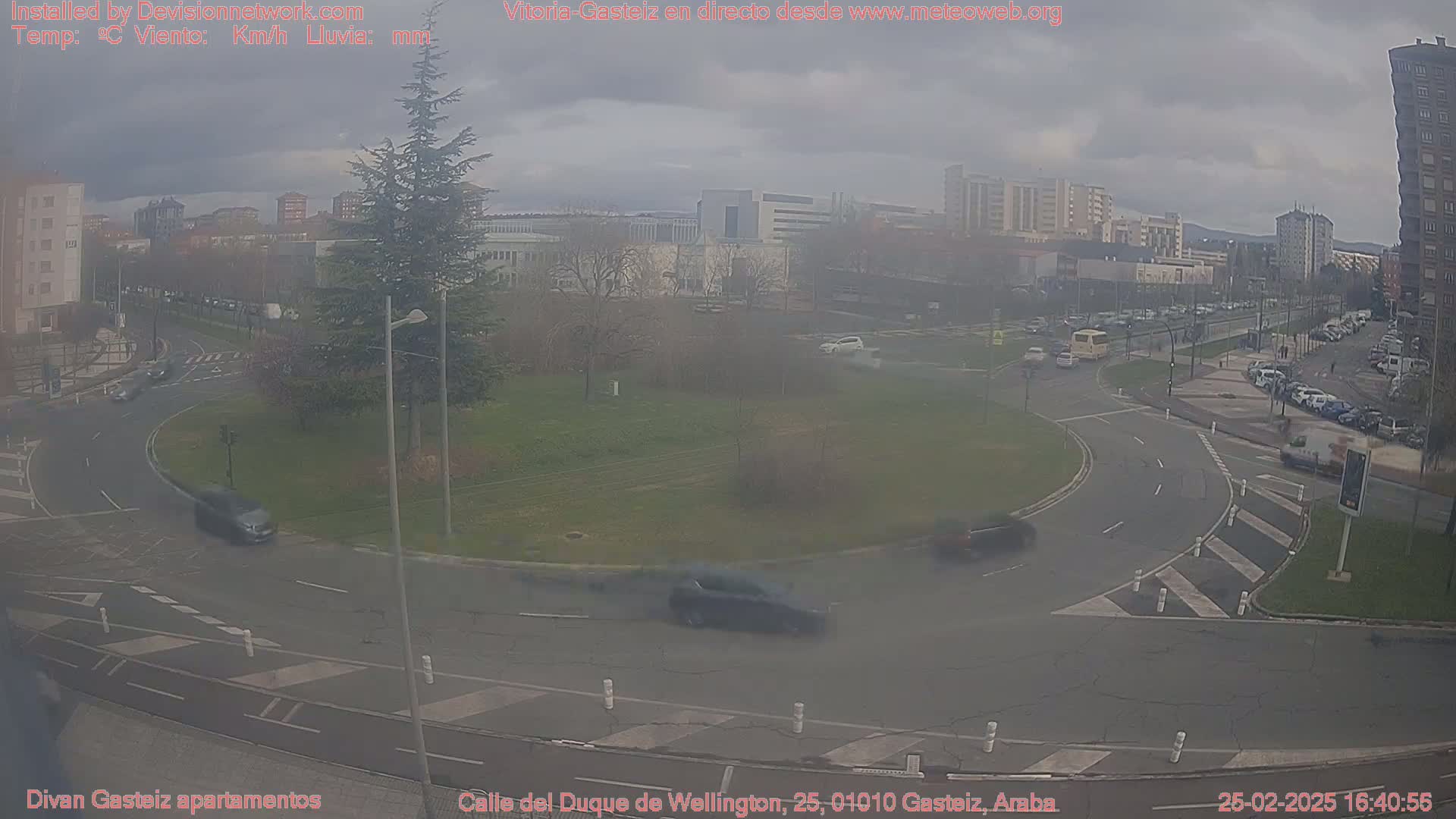 A hazy, overcast day reveals a traffic circle surrounded by buildings and greenery, with several cars navigating the roundabout.